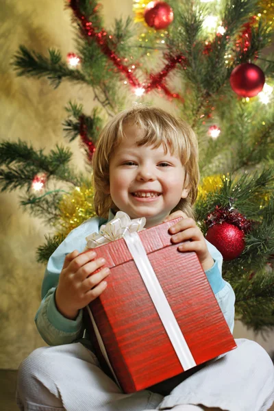 Lycklig pojke med julklapp nära julgran — Stockfoto