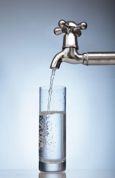 Wasser wird aus dem Wasserhahn in ein Glas gegossen — Stockfoto