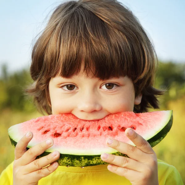 Glückliches Kind isst Wassermelone im Garten — Stockfoto