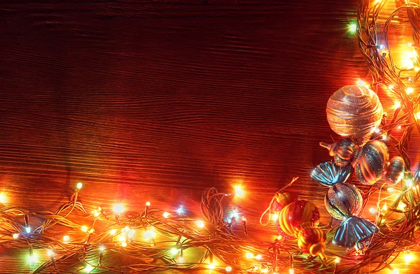 Guirlandas de Natal de lâmpadas em um fundo de madeira . — Fotografia de Stock