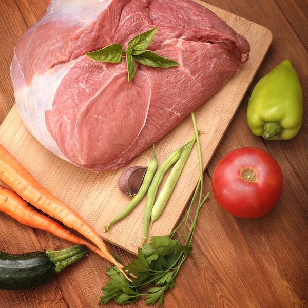 Сырое мясо и овощи на разделочной доске — стоковое фото