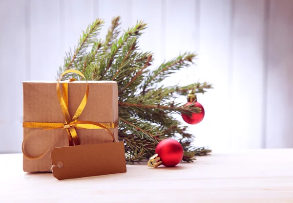 Новорічна ялинка з подарунковою коробкою та прикрасами на дерев'яному фоні — стокове фото