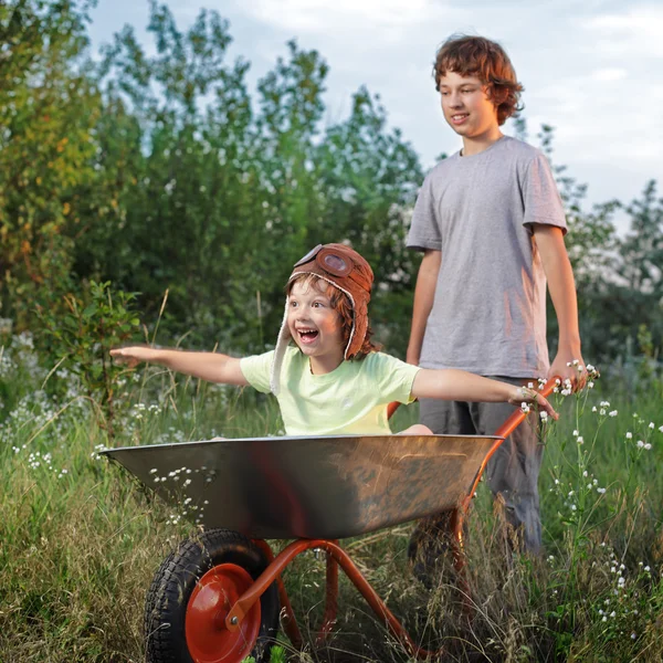 Zwei Freunde spielen im Flugzeug mit einem Gartenkarren — Stockfoto