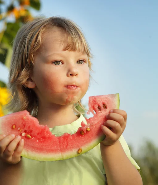 Lyckligt barn äta vattenmelon i trädgården — Stockfoto