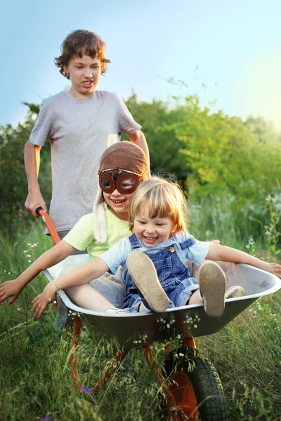 Three brother playing in the plane using a garden carts — Stock Photo, Image