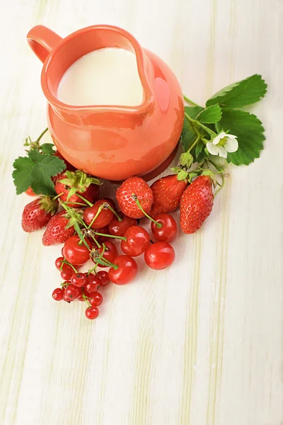 Ripe juicy berries and jug on the table — Stock Photo, Image