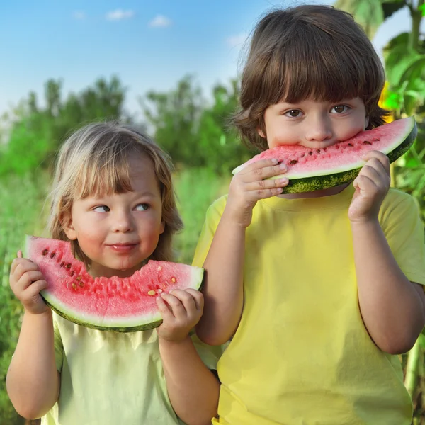 Glückliches Kind isst Wassermelone im Garten — Stockfoto