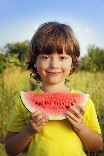 Criança feliz comendo melancia no jardim — Fotografia de Stock