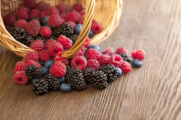 Verschiedene Beeren in einem Korb auf einem Holztisch — Stockfoto