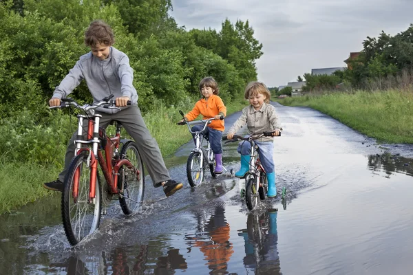 Bambini felici stanno attraversando una pozzanghera — Foto Stock