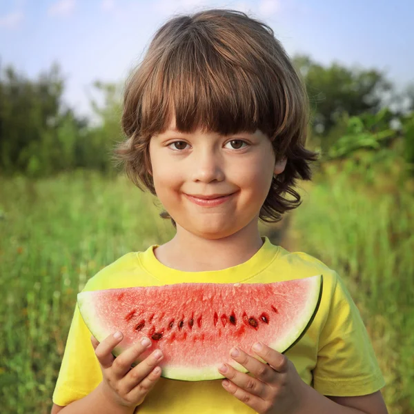 Niño feliz comiendo sandía en el jardín — Foto de Stock