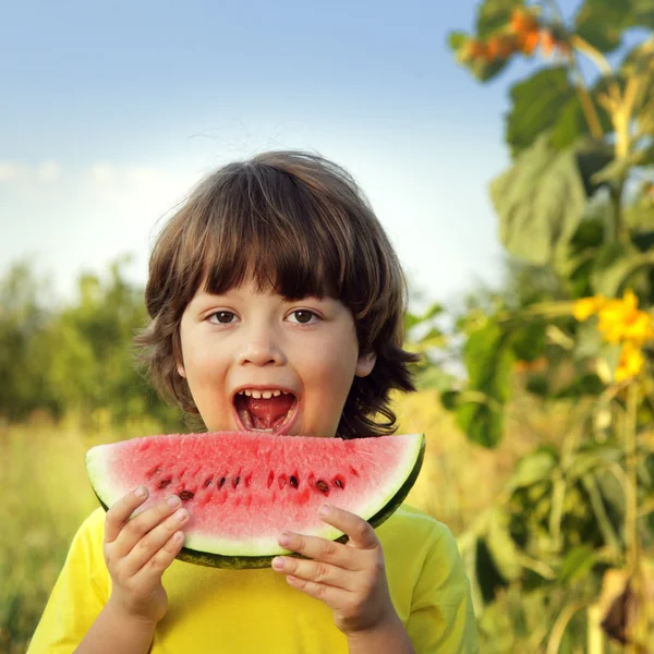 Szczęśliwe dziecko jedzenie arbuza w ogrodzie — Zdjęcie stockowe