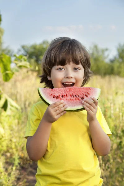 Lyckligt barn äta vattenmelon i trädgården — Stockfoto