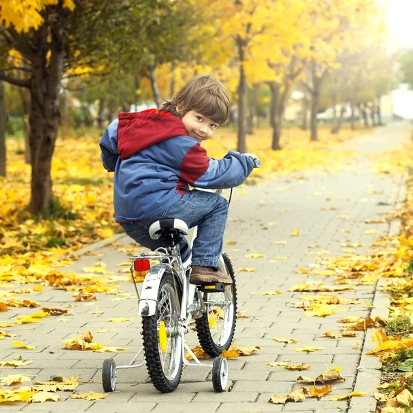 Niño montando en bicicleta en el parque de otoño — Foto de Stock