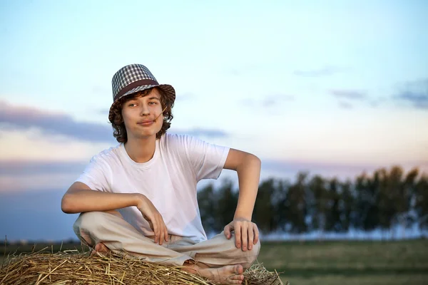 Jongen in een hooiberg in het veld — Stockfoto