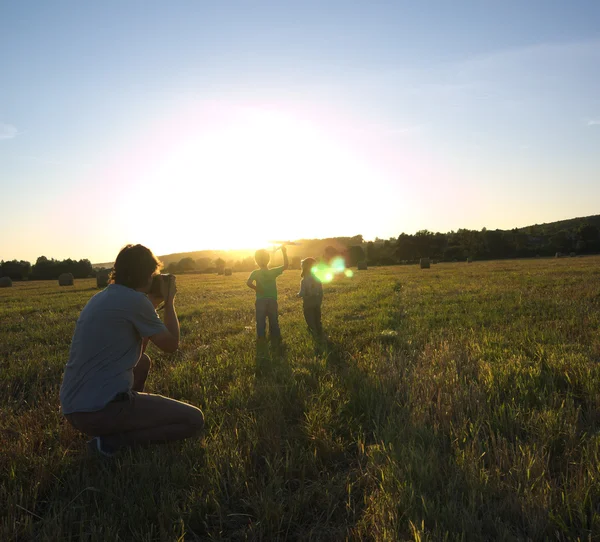 Photographe prenant des photos d'enfants sur une prairie en pente — Photo