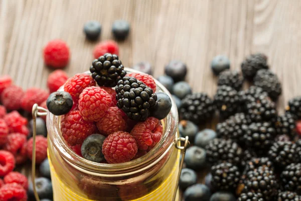 Verschiedene Beeren in einem Korb auf einem Holztisch — Stockfoto