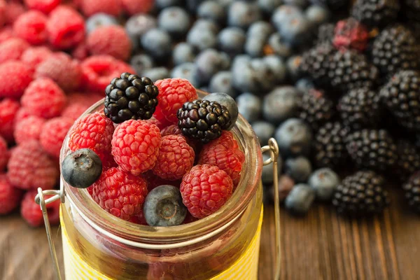 Verschiedene Beeren in einem Korb auf einem Holztisch — Stockfoto