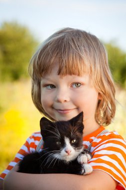 Bir yavru kedi ile mutlu çocuk