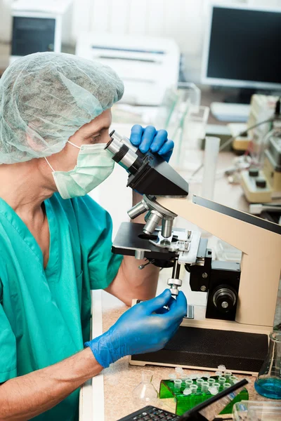 Scientist looking into a microscope — Stock Photo, Image