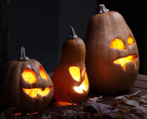 Jack o lanternas Halloween rosto de abóbora no fundo de madeira — Fotografia de Stock