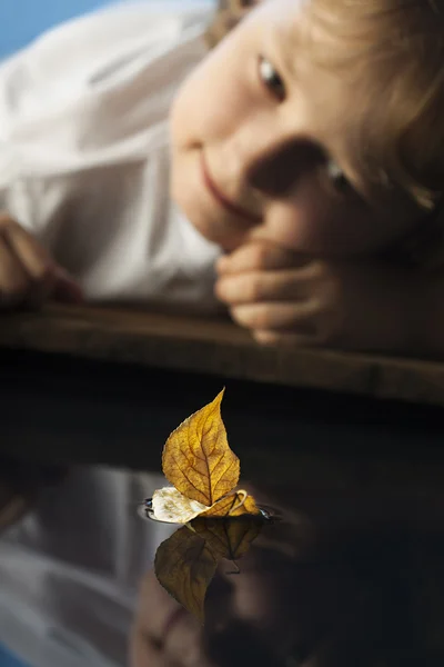 Boy play with leaf ship in water — Stock Photo, Image