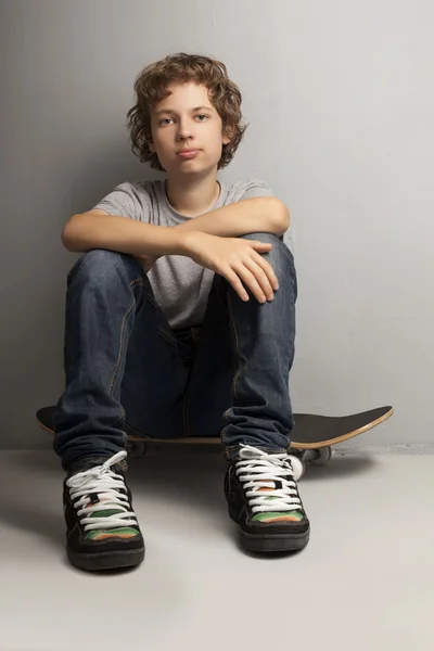 Щасливий хлопчик сидить на скейтборді — стокове фото