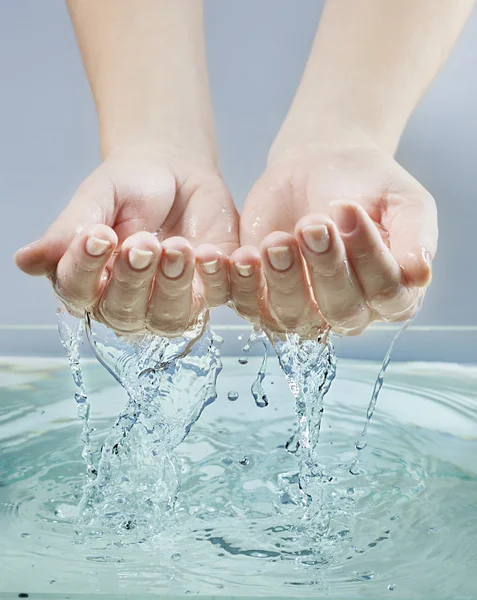 Vrouw handen in blauwe water — Stockfoto