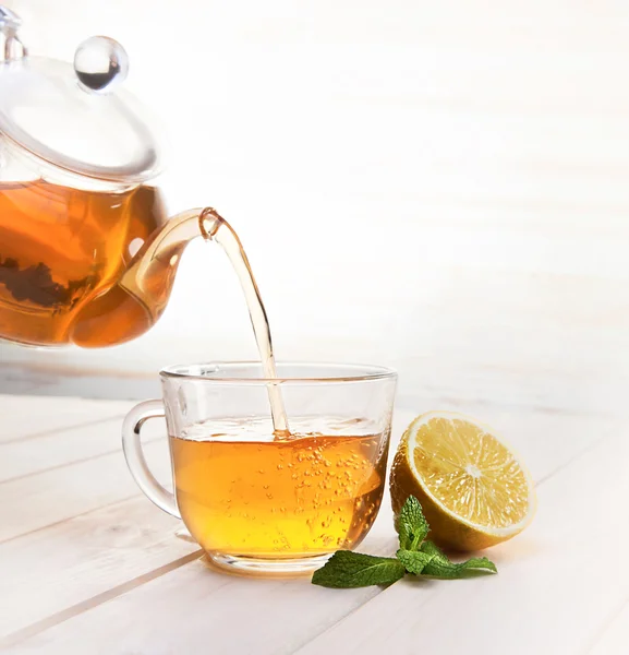 Cup of tea, glass teapot, mint and lemon on wooden table — Stock Photo, Image