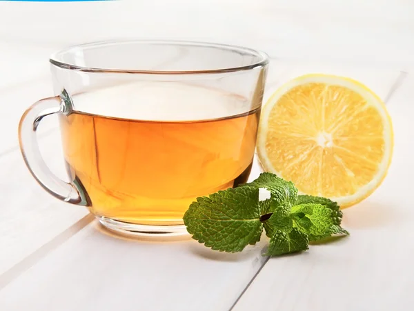 Tasse Tee, Minze und Zitrone auf Holztisch — Stockfoto
