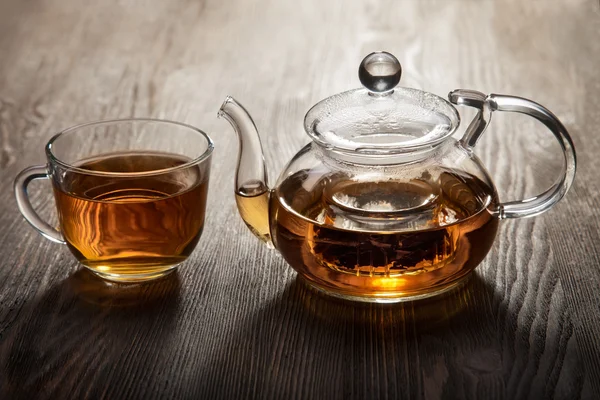 Tetera y taza de té sobre mesa de madera —  Fotos de Stock