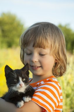 Bir yavru kedi ile mutlu çocuk