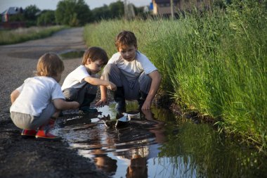 su birikintisi içinde üç çocuk oyun