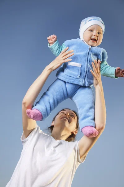 Mother throws baby on blue beckground — Stock Photo, Image