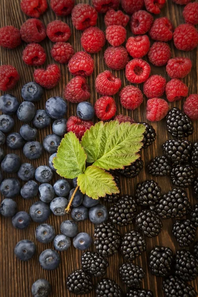 Himbeeren und Brombeeren auf dem Holztisch verstreut — Stockfoto