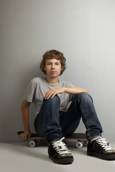 Glücklicher Junge sitzt auf Skateboard — Stockfoto