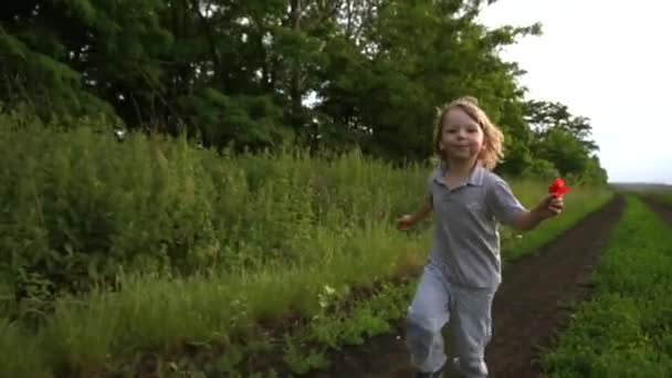 Счастливый ребенок бежит по сельской дороге — стоковое видео