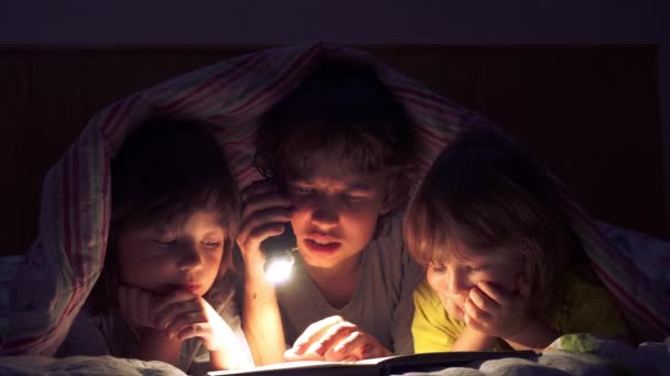 Dzieci, czytanie książki pod kołdrą — Wideo stockowe