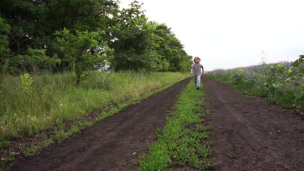 Gelukkig kind wordt uitgevoerd op een landelijke weg — Stockvideo