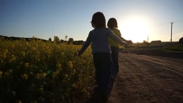 Niños corriendo cerca del prado de flores amarillas — Vídeo de stock