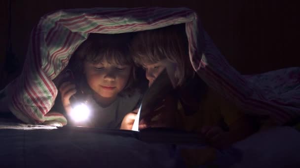 Les enfants lisent un livre sous les couvertures — Video