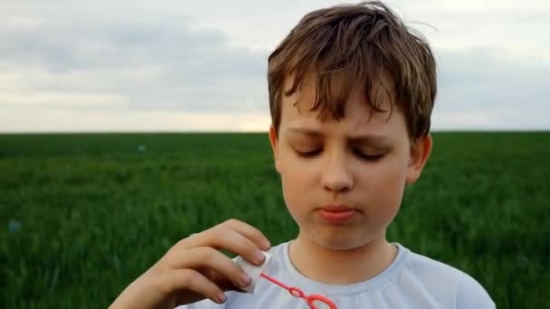 Мальчик надувает пузыри на улице — стоковое видео