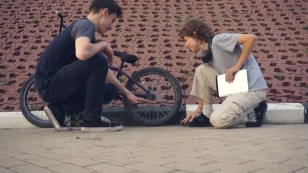 Teenagers talking in the park about extreme bike — Stock Video