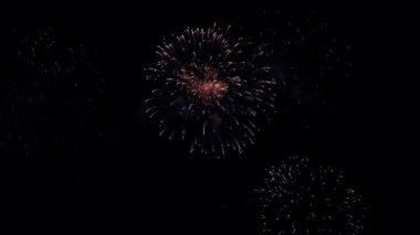 4K. Gerçek havai fişek arka planı. Gece gökyüzünde parlayan havai fişekler. Işıl ışıl parlıyor. Yeni yıl arifesi havai fişek kutlaması. Renkli Yeni Yıl Havai fişekleri