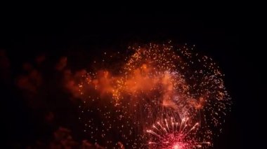 4K. Gerçek havai fişek arka planı. Gece gökyüzünde parlayan havai fişekler. Işıl ışıl parlıyor. Yeni yıl arifesi havai fişek kutlaması. Renkli Yeni Yıl Havai fişekleri