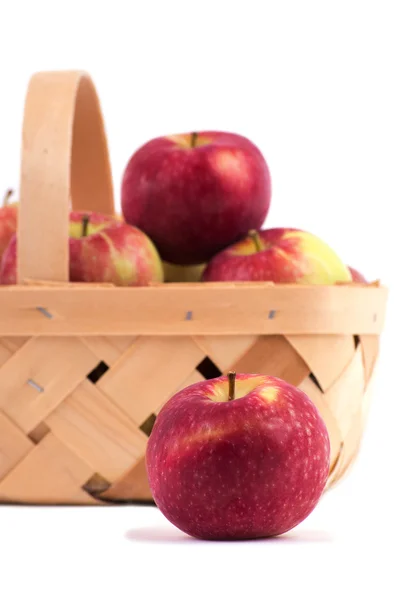 Яблоко перед корзиной, полной яблок, на белом — стоковое фото