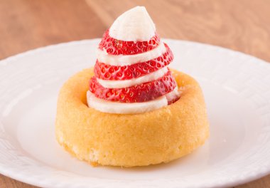 Tatlı kabuk dilimlenmiş muz ve çilek beyaz tabakta ile