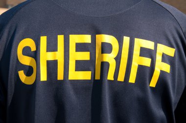 Closeup image of a back of a sheriff's deputy, with text sheriff in yelllow letters clipart