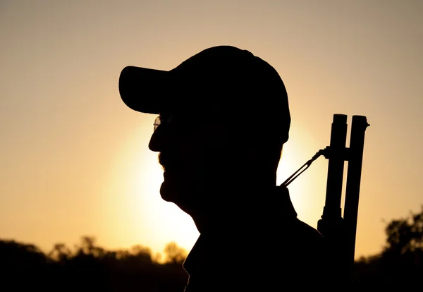 Silhuetten av en man med ett hagelgevär mot soluppgången — Stockfoto