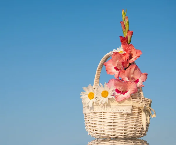 White wicker basket with pink and white flowers against clear blue sky — Stock Photo, Image